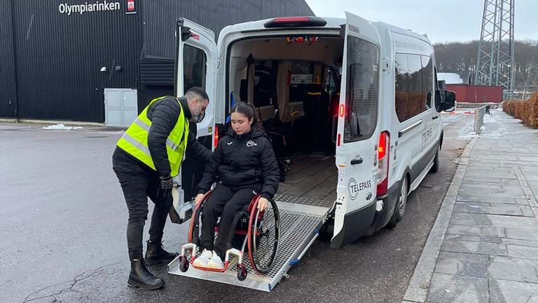 Telepassförare hjälper en bordtennisspelare i rullstol under Para-VM